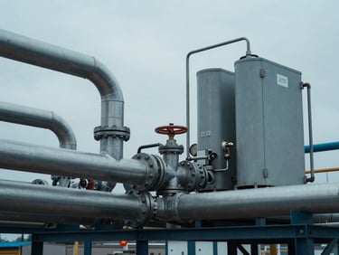 Industrial clean energy infrastructure with heavy steel pipes and fuel cell testing equipment, cool overcast daylight, sharp technical details, desaturated blues, 35mm