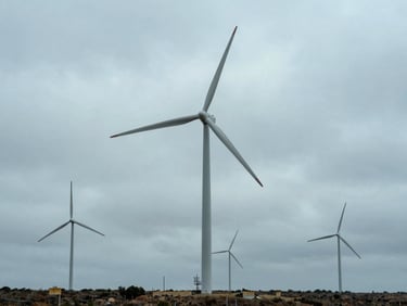 Large-scale wind installation integrated into an overcast landscape, wide environmental shot, desaturated blues, 35mm