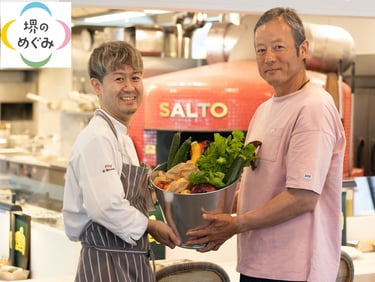 SALTOシェフ吉本さんと「じいじのバケツ」中井さんが新鮮な堺産野菜を手に店内で並ぶFARM TO TABLEの連携イメージ写真|堺市のニュースならサカイタイムズ