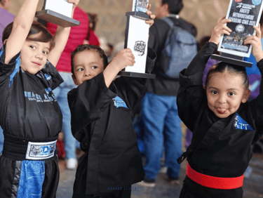 niños levantando trofeos después de torneo de prekarate