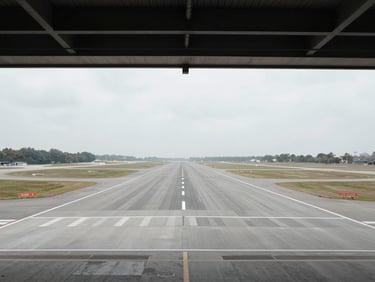 Symmetrical wide-angle shot of empty airport runway, flat overcast daylight, desaturated industrial tones, 35mm