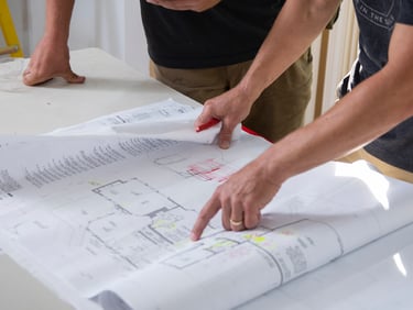 a man and woman are looking at a blueprinted plan