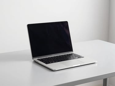 Clean product shot of a sleek open laptop on a minimalist light gray desk, bright natural daylight, crisp focus, 35mm