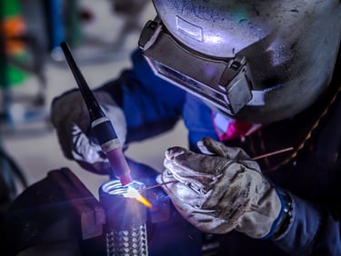 Worker wielding a circular stainless steel pipe at Jain Stainless Steel 