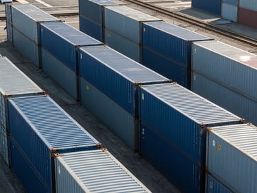 High-angle shot of intermodal rail terminal with shipping containers stacked in neat grids, cool morning daylight, sharp focus, 35mm