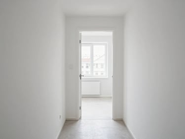 Interior of a compact Klaipėda apartment, clean white walls, entry hallway leading to a bright room, natural daylight from a north-facing window, no furniture clutter, functional and tidy