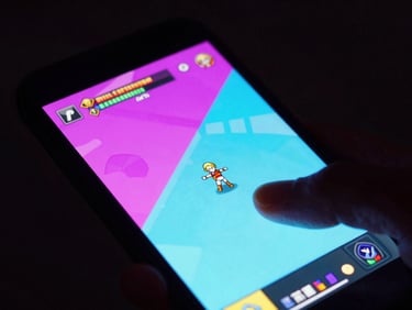 Tight macro shot of a mobile device showing vibrant RPG gameplay, neon magenta and cyan screen glow casting onto hands, dark background