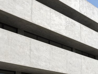 Crisp architectural photography of a modern concrete building facade under bright natural daylight, clean structural lines, realistic concrete texture, 35mm