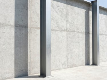 Straight-on elevation shot of clean, newly poured concrete walls and structural steel pillars, bright daylight, sharp shadows