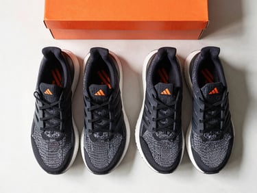Overhead flatlay of Adidas Ultraboost running shoes on a clean surface with a subtle orange box accent, daylight
