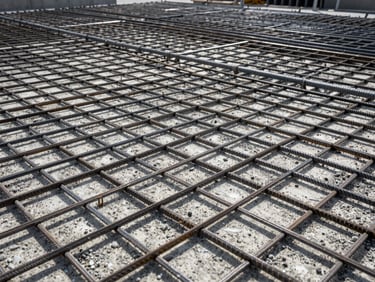 Close-up of raw poured concrete over thick steel rebar grids, high contrast lighting, industrial realism.