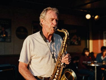 Candid portrait of an older man with a saxophone in a warm, dimly lit local jazz club, soft golden-hour stage lighting, authentic 35mm film grain.