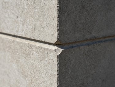 Macro close-up of a concrete join, sharp architectural daylight casting deep shadows on raw stone texture, precise alignment.