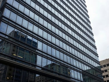 Modern corporate office building facade in Bogotá, overcast daylight reflecting off glass windows, cool steel blue tones, architectural perspective, 35mm editorial.