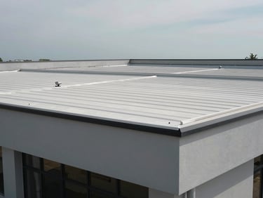 Straight-on daylight photograph of a completed commercial building exterior showing the full roof structure — flat membrane roofing visible, parapet walls clean, equipment mounts installed, overcast sky above