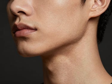 Close-up shot of smooth skin on a jawline, highlighting structural definition and natural radiance, dark editorial background.