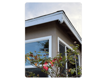 a house with a tree in the foreground and a window with a sky background