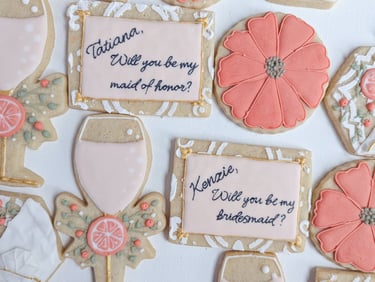 Cookies for to ask bridesmaids to be in a wedding party, wine, oranges, flowers