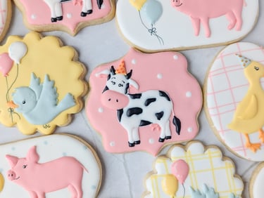Cookies with cows, birds, pigs, and ducks in party hats in pink, white, blue, yellow