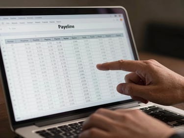 Close-up of hands scrolling through a spreadsheet on a laptop showing pipeline and payback period columns, soft studio light, dark background, numbers clearly legible on screen