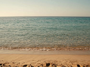 A quiet sandy cove in Greece with crystal-clear turquoise water, soft golden hour light, low horizon, 35mm