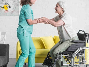 A compassionate home care worker assists an elderly woman in rising from her wheelchair with care.