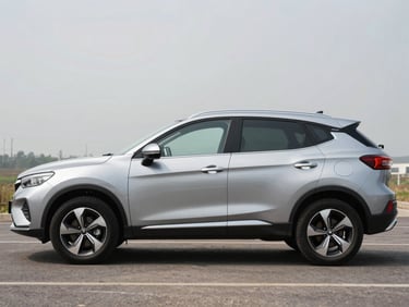 Side profile of a silver compact SUV parked on an open lot under natural daylight, slight overcast sky, full vehicle visible