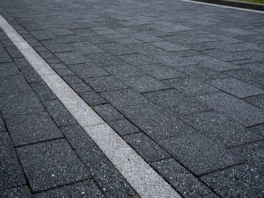 A beautifully paved driveway with anthracite interlocking stones, perfect drainage channels on the side, clean edges.