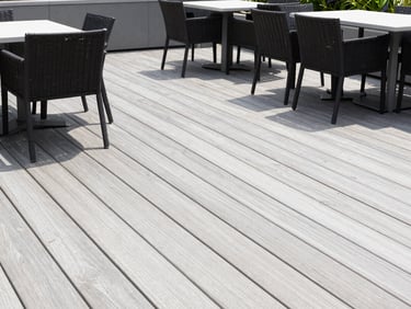 Clean wooden deck with patio furniture, bright daylight, professional editorial style.