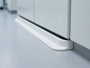 Close-up of a flawless white sanitary cove transition (curva sanitaria) between an epoxy floor and a cleanroom wall in a pharmaceutical laboratory, bright sterile lighting.