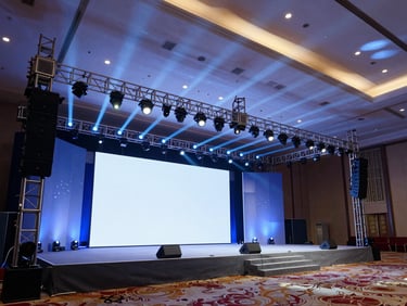 Large-scale corporate conference hall setup, grand stage design, precise structural framing, dramatic blue and white lighting.