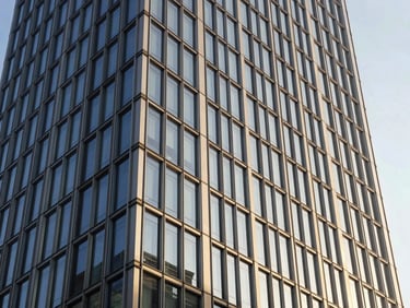 Modern glass commercial tower facade with sleek steel beams, bright natural daylight, clean architectural lines.