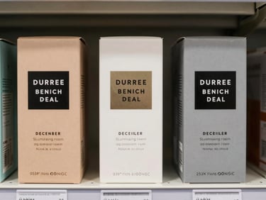 Three product boxes on a retail shelf, studio even-lighting, tight environmental shot showing label typography and color blocking, minimal background, no human presence