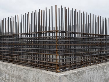 Geometric composition of steel rebar against a concrete foundation, overcast daylight, desaturated.