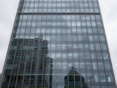 Straight-on architectural elevation of a modern glass office tower facade, overcast daylight, sharp structural lines.