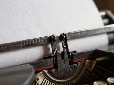 Extreme close-up of a vintage typewriter key striking textured heavy paper, deep shadows, harsh side lighting