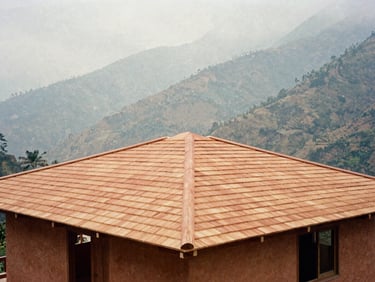 Wide environmental shot of a newly built timber roof on a home in the misty mountains of Tlacolulan, soft diffused daylight, warm terracotta tones.