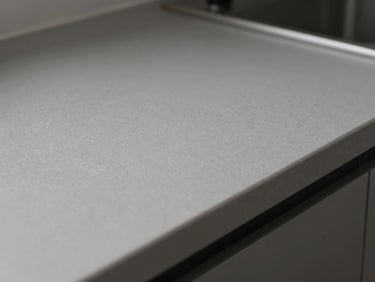 Extreme close-up of a freshly cleaned kitchen countertop surface, shadowless studio lighting, grout lines and fixture edges in sharp focus, no people, no objects placed on surface