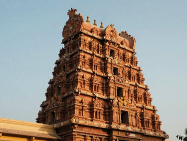 Towering gopuram of a Tamil Nadu temple reflecting warm evening sunlight, rich terracotta tones, documentary style