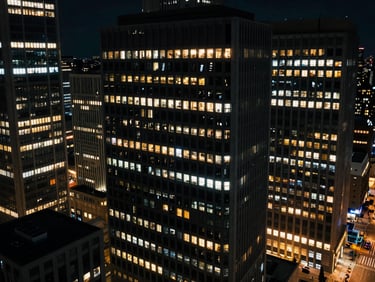 High-altitude architectural view of a financial district at night, with precise grid lights, low-key cool lighting, sharp technical details, deep obsidian and amber tones, 35mm