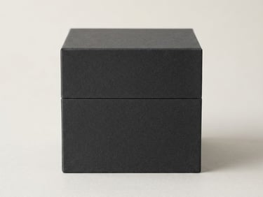 Pristine empty rigid cosmetic box with sharp 90-degree edges and matte charcoal texture, soft diffused studio lighting, neutral minimalist background, 85mm