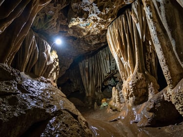 Damp limestone formations of Cavernas del Nus, headlamp light reflecting on wet rock, authentic adventure photography