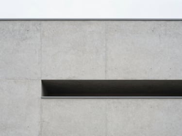 Minimalist architectural photography of a modern concrete building facade, soft diffused overcast daylight, clean structural lines, light gray and slate tones, 35mm