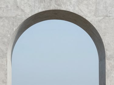 A clean, modern concrete archway framing a soft blue sky, minimalist architectural photography, 35mm
