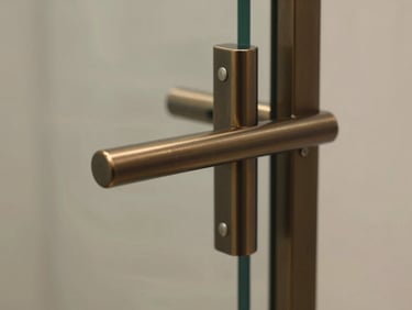 Close-up of minimalist architectural hardware in oil-rubbed bronze, fitted perfectly into a glass and steel frame.