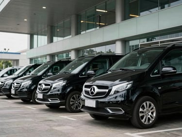 Fleet of black executive vans parked elegantly outside a modern convention center, crisp daylight, professional setting.