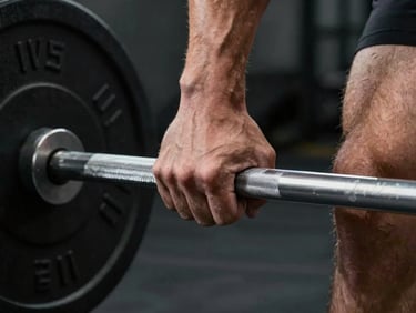 Close-up of hands gripping a barbell at the start of a deadlift, knuckles white, gym chalk visible, studio strobe lighting from the side, dark background