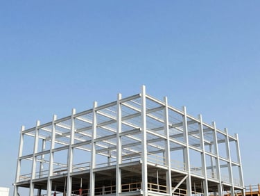 Active commercial construction site with clean steel frameworks rising under a clear blue sky, wide-angle lens