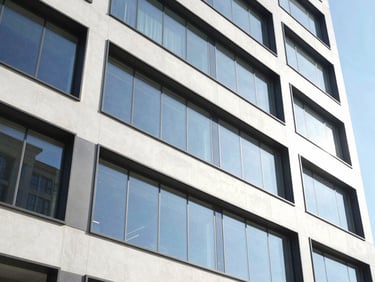 Close-up of modern commercial building facade with clean glass and concrete lines, bright natural daylight