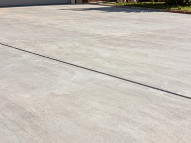 Close-up of a newly finished concrete driveway with clean hand-tooled joints, bright sunlight casting sharp shadows